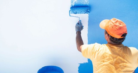 A contractor paints a wall blue. | How Occupation Impacts Small Business Commercial Vehicle Insurance Premiums