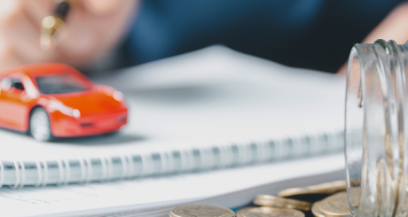 toy car sitting on stack of paper near jar of coins
